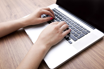 Fototapeta premium Close-up of businesswoman's hands using laptop at table