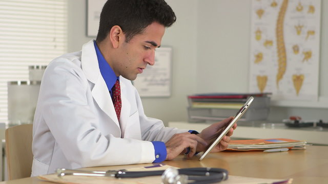 Hispanic doctor working on tablet in office