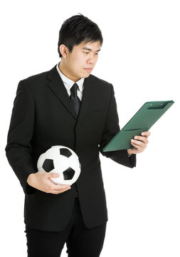 Businessman looking at file pad and holding soccer ball