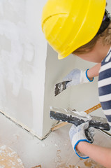 Female plasterer repairs wall with spackling paste