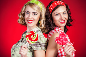 Beautiful pinup girls with lollipop on red background