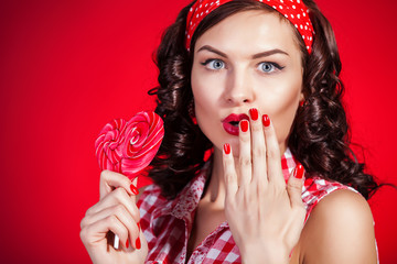 Young pin-up girl with lollipop on red background