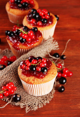 Tasty muffins with berries on wooden table