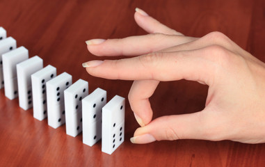 Hand pushing dominoes on wooden background