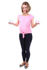 Naklejka premium Young pregnant woman holding blue and pink baby shoes isolated