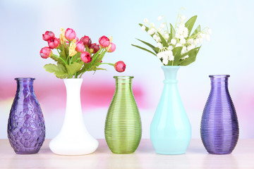 Different decorative vases on shelf on light background