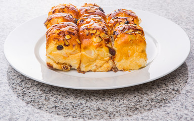 Homemade sweet bun with almond and raisins on a white plate