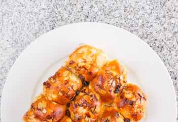 Homemade sweet bun with almond and raisins on a white plate