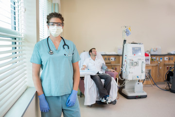 Nurse In Protective Clothing With Patient Receiving Dialysis