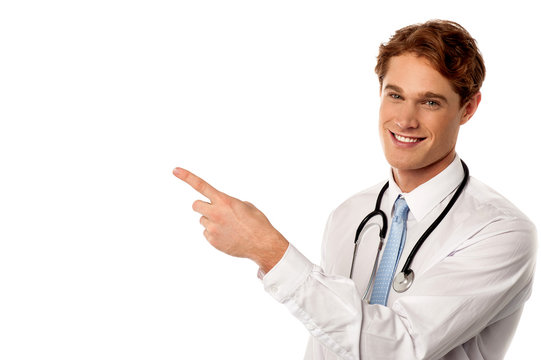 Smiling young physician pointing away