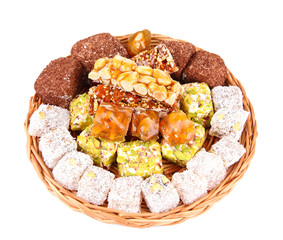 Tasty oriental sweets on wicker tray, isolated on white