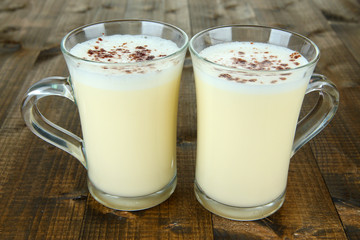Cups of eggnog on wooden background