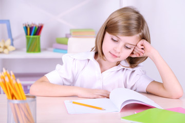 Little girl sitting at desk in room