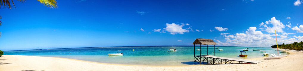 Panoramic view of tropical beach with jetty and boats