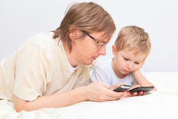 father and son with mobile phones at home