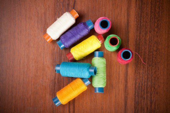 colorful spools of thread on a wooden background