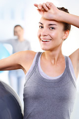 Naklejka premium Kobieta na siłowni ociera pot z czoła