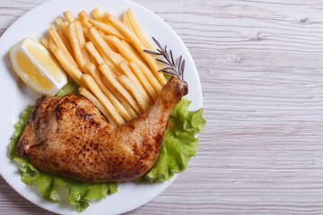 Portion of chicken legs, french fries on a white plate. top view