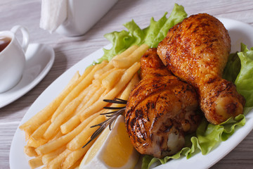 Two fried chicken drumsticks with french fries