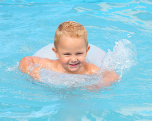 Fototapeta na wymiar Happy boy with a life ring enjoying life in the swimming pool.