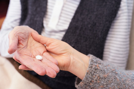 Hands of senior patient and caregiver with medication