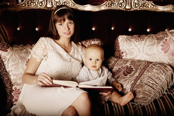 Mother with a small child in the interior reading a book togethe