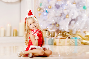 Obraz na płótnie Canvas Beautiful little Santa girl near the Christmas tree. Happy girl