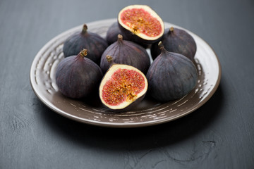 Plate with ripe figs over black wooden background