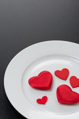 Fototapeta na wymiar red hearts on a white plate, close-up