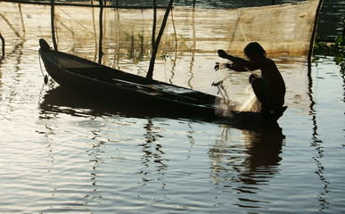 fisherman sitting on row boat, pick up the net