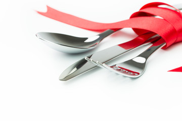 Fork, spoon and knife tied up with red ribbon
