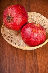 pomegranate fruit in a wicker basket on a wooden table