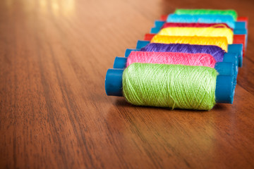 colorful spools of thread on a wooden background