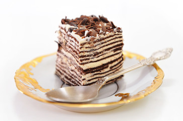 Cake with spoon on golden saucer.