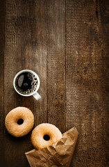 Sugared doughnuts and coffee on rustic wood