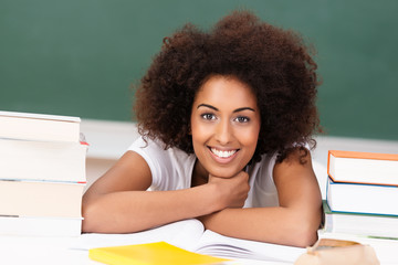 studentin mit afro-frisur zwischen bücherstapeln
