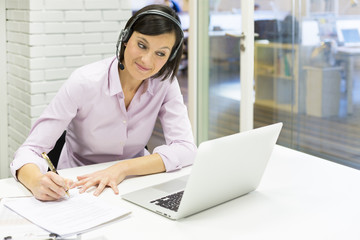 Businesswoman in the office on the phone, headset, Skype