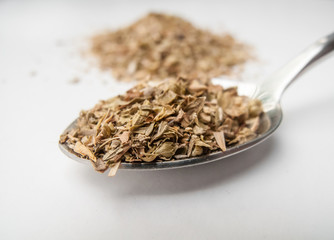 Oregano whole on spoon in white background.
