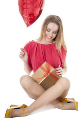 Beautiful woman with red heart balloon and a gift box sitting on