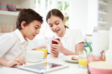 Obraz na płótnie Canvas Schoolchildren With Digital Tablet And Mobile At Breakfast