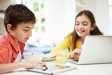 Children With Digital Tablet And Laptop At Breakfast