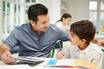 Father Helping Son With Homework Using Digital Tablet