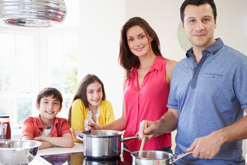 Hispanic Family Cooking Meal At Home Together