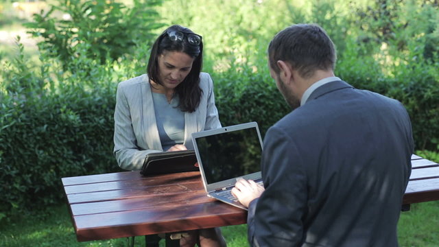 businesswoman sitting by the table with her partner and similing