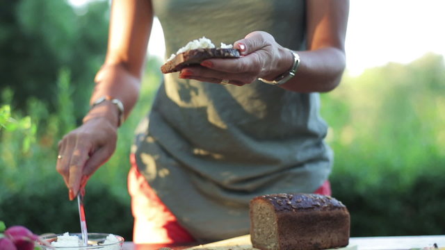 woman's hands applying white cheese on a slice of bread