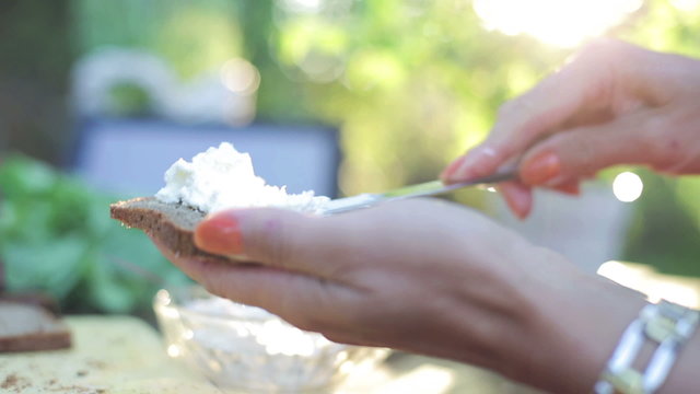 woman's hands applying white cheese on a slice of bread