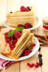 Delicious pancakes with berries, jam and honey on wooden table