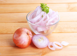 Onion cut with rings in bowl on wooden table close-up
