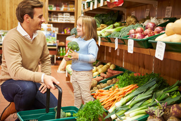 Father And Daughter Choosing Fresh Vegetables In Farm Shop