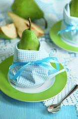 Pears in napkins on plates on wooden table close-up